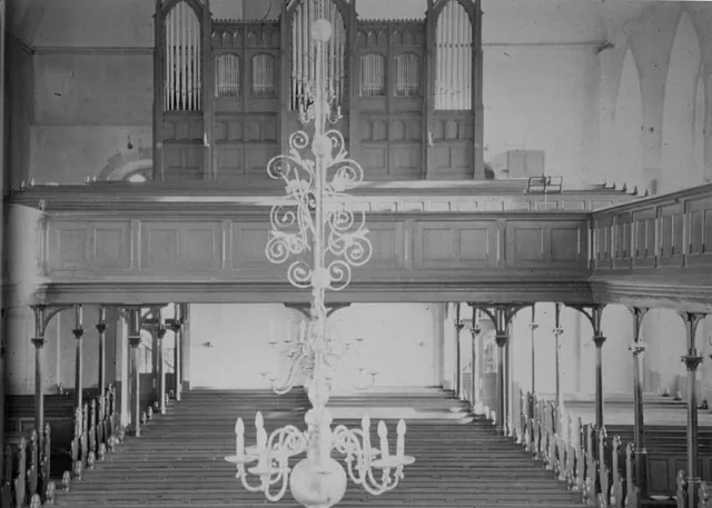  Schwarzweißbild der Orgelempore mit Leuchter im Vordergrund