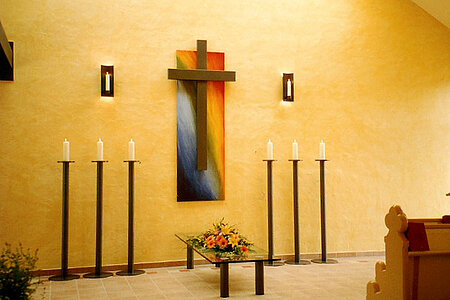 Vordere Wand der Friedhofshalle mit Kreuz und Leuchtern