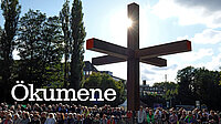 Menschen unter Wegkreuz vor Sonne